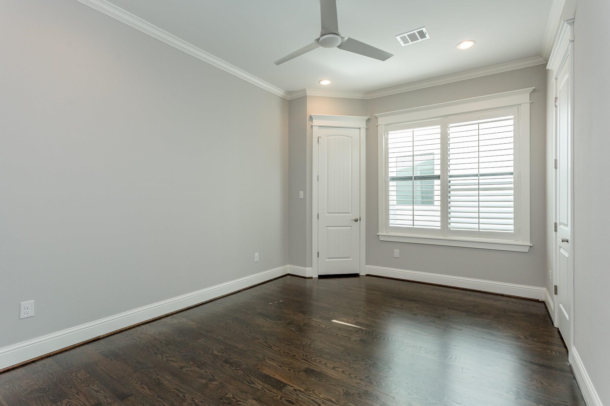 2035 Sheridan Street, Unit A Houston, TX 77030 - Photo 27 of 41 an empty room with wooden floor and windows with curtains