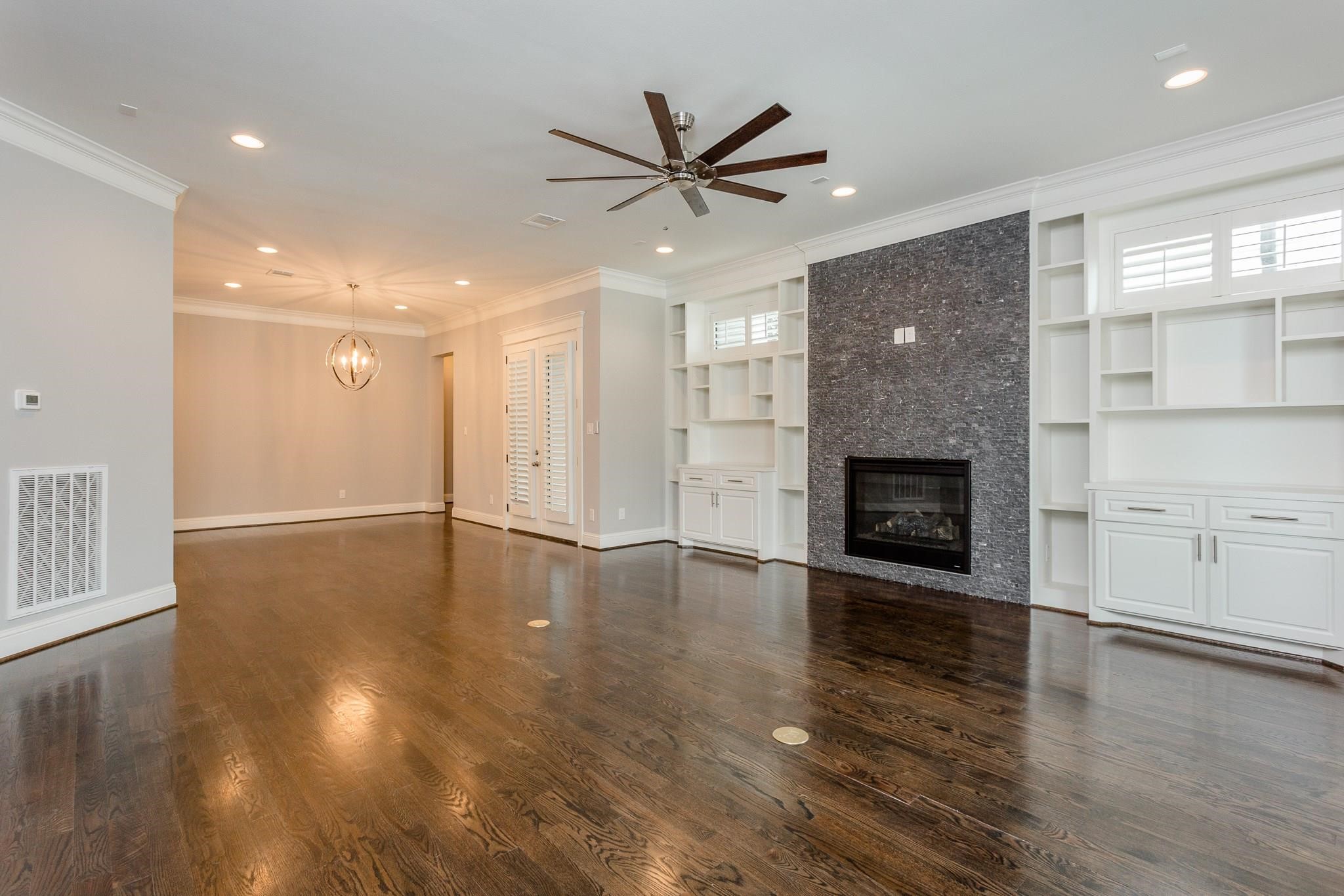 2035 Sheridan Street, Unit A Houston, TX 77030 - Photo 4 of 41 an empty room with wooden floor a ceiling fan a fireplace and windows