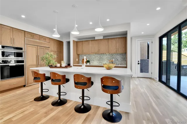 a kitchen with stainless steel appliances kitchen island granite countertop a refrigerator a stove a sink and chairs with wooden floor