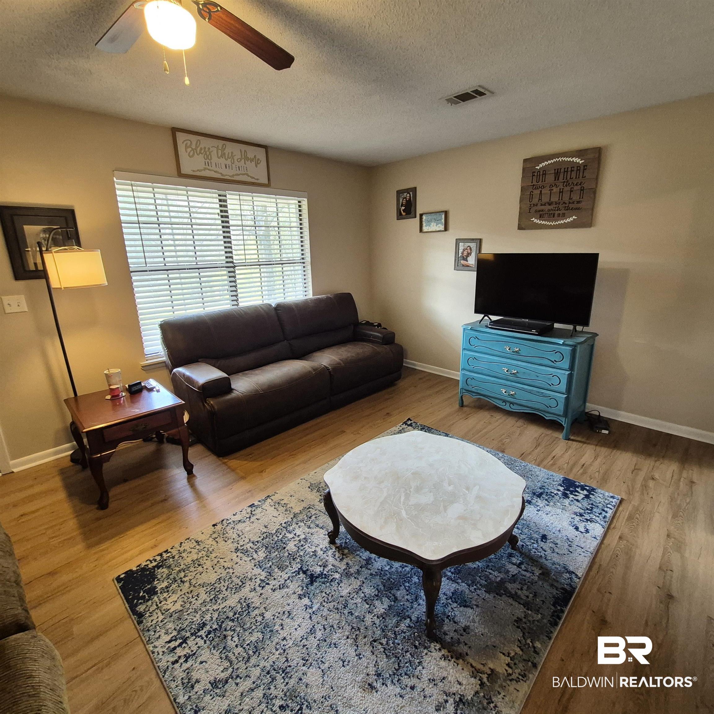 721 Perryman Street Evergreen, AL 36401 - Photo 3 of 26 Living room with a ceiling fan, light wood-style floors, and a textured ceiling