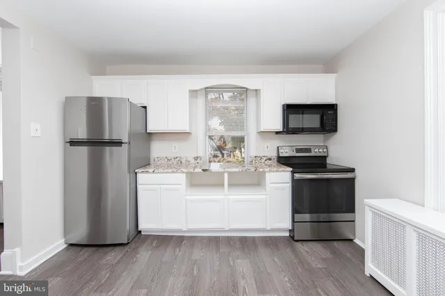 a kitchen with a refrigerator stove and wooden floor