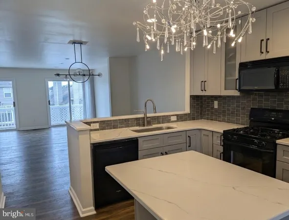 a kitchen with stainless steel appliances a sink a stove a microwave a center island and cabinets