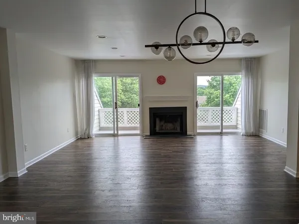 an empty room with wooden floor fireplace and windows