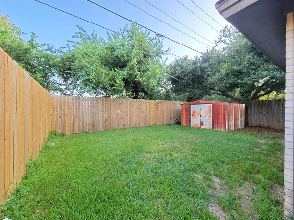 a view of a backyard with large trees and wooden fence