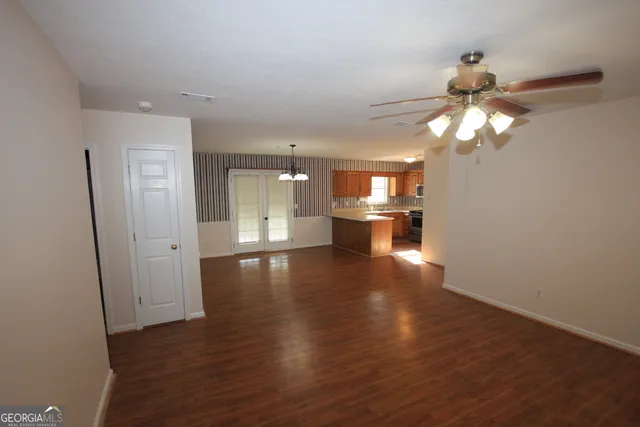 a view of empty room with wooden floor and fan