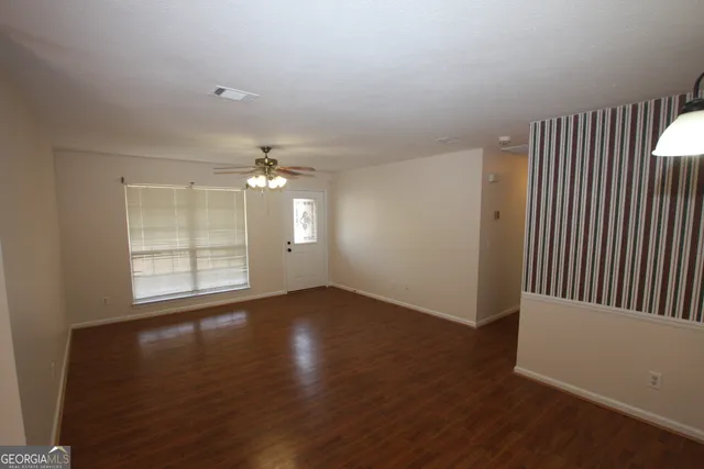 an empty room with wooden floor cabinet and windows