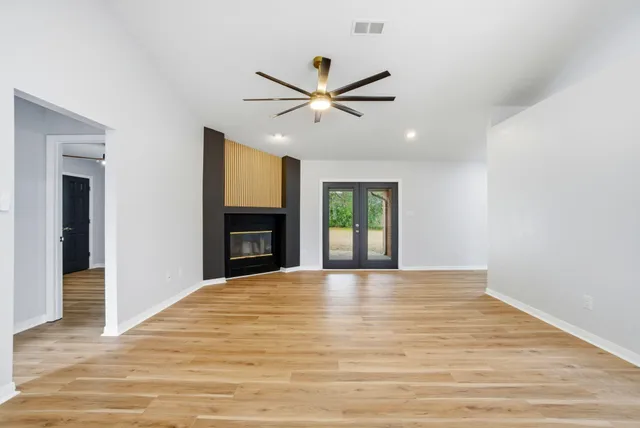 a view of an empty room with window and wooden floor