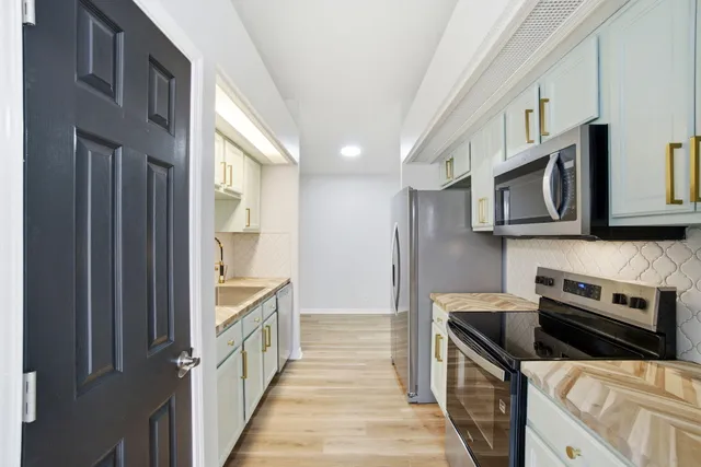 a kitchen with stainless steel appliances a stove a microwave and a window