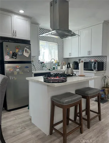 a kitchen with stainless steel appliances kitchen island granite countertop a table chairs sink and cabinets