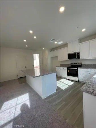 a kitchen with granite countertop white cabinets and stainless steel appliances