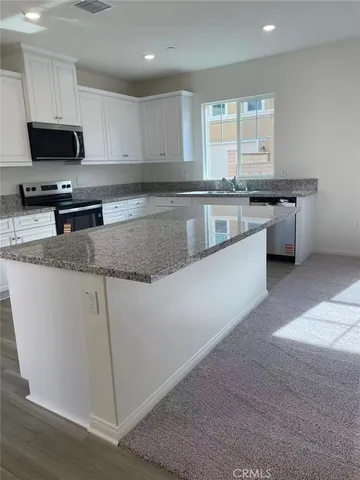 a kitchen with granite countertop a sink a counter top space appliances and cabinets