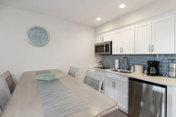 a kitchen with a sink dishwasher a stove top oven a refrigerator with a dining table and chairs