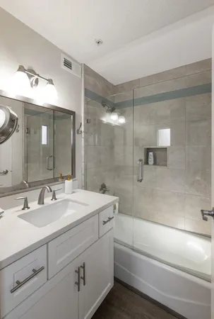 a bathroom with a bathtub shower sink vanity and mirror