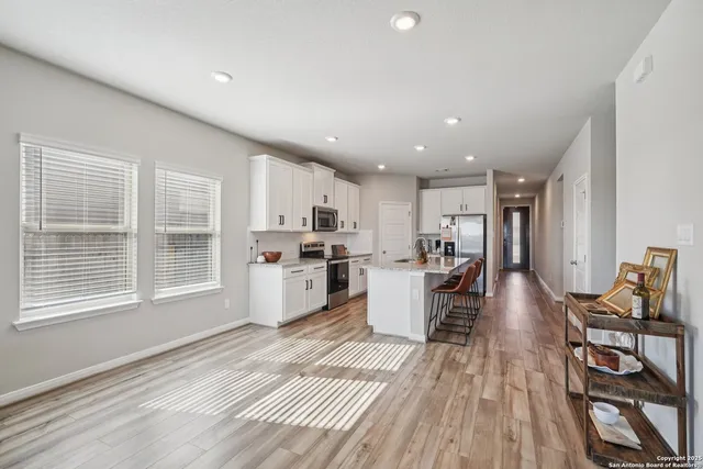 a large white kitchen with wooden floor and a window