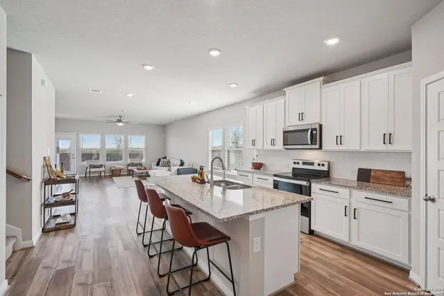 a kitchen with stainless steel appliances a stove a sink a oven a dining table and chairs