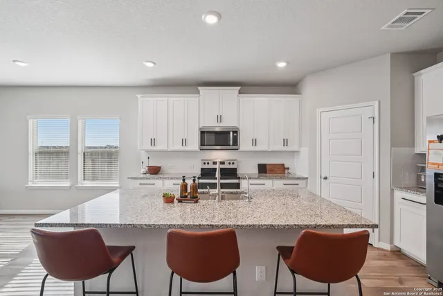 a kitchen with stainless steel appliances granite countertop a stove a sink a microwave a dining table and chairs