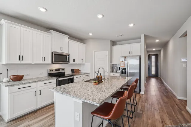 a kitchen with stainless steel appliances granite countertop a kitchen island hardwood floor sink and stove