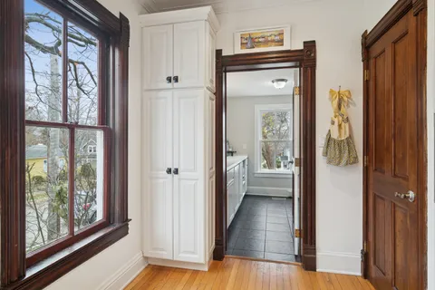 a view of a hallway with wooden floor and windows with an outdoor view
