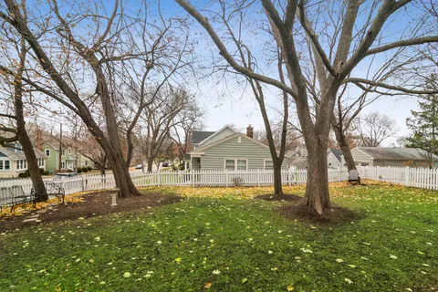 a front view of a house with a yard and large tree