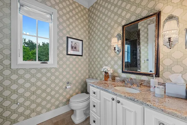 a bathroom with a granite countertop toilet sink and mirror