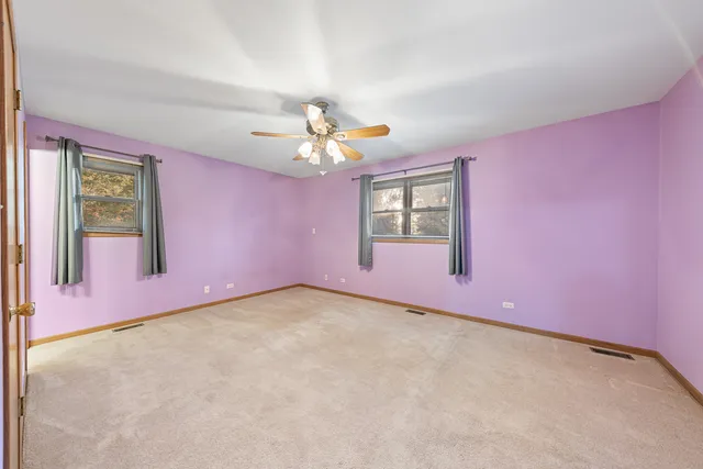 an empty room with windows and chandelier fan