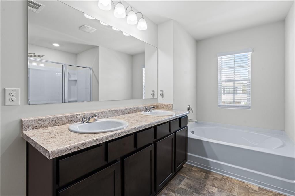 5367 Pennington Court Atlanta, GA 30349 - Photo 18 of 33 a bathroom with a granite countertop sink a large mirror and a bathtub