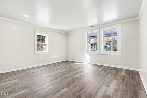 a view of an empty room with wooden floor and a window