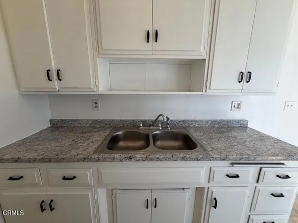 a kitchen with granite countertop white cabinets and a sink