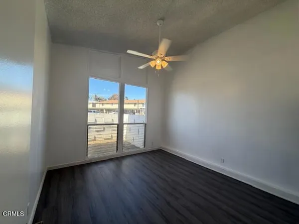 an empty room with wooden floor fan and windows