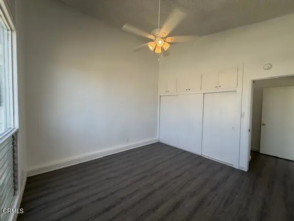 an empty room with wooden floor and fan