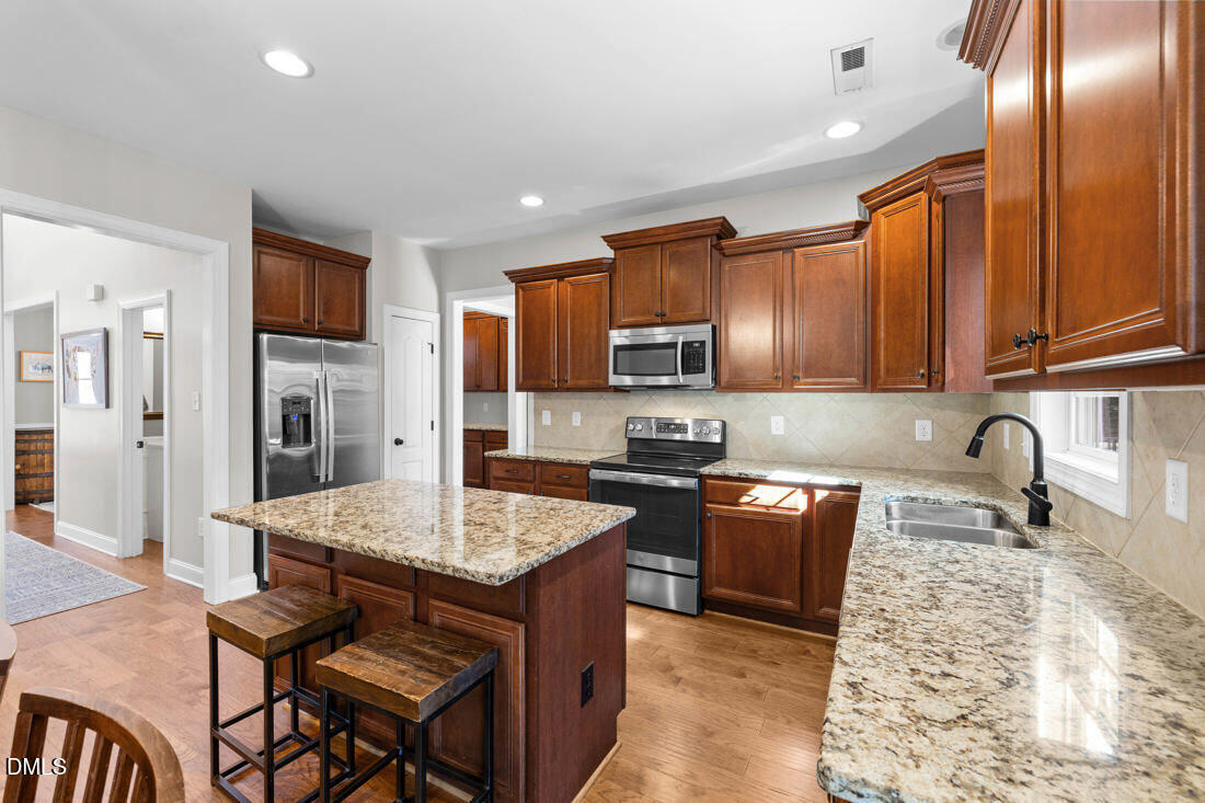 170 Valley Pines Circle Spring Lake, NC 28390 - Photo 19 of 55 a kitchen with granite countertop wooden cabinets a refrigerator a stove a oven with granite countertops and cabinets