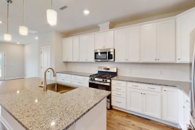 a kitchen with stainless steel appliances granite countertop a sink stove and cabinets