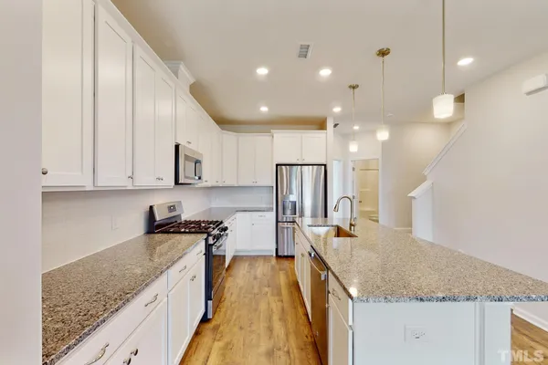 a kitchen with granite countertop a sink a stove and cabinets