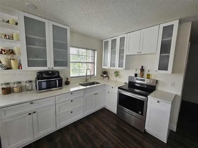 a kitchen with granite countertop white cabinets and white appliances