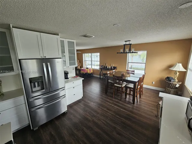 a kitchen with stainless steel appliances granite countertop a refrigerator a stove a dining table and chairs with wooden floor