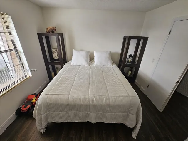 a bedroom with a bed a mirror and wooden floor