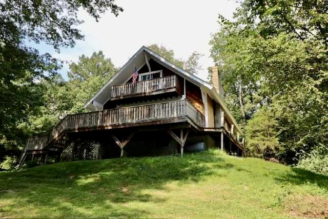 a view of a wooden house with a big yard and large trees