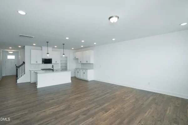 a view of kitchen with kitchen island a sink wooden floor and a refrigerator