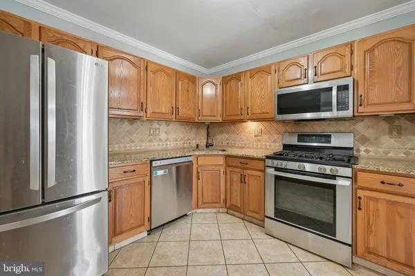 a kitchen with stainless steel appliances granite countertop a stove top oven a sink and a refrigerator