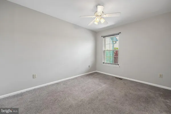 an empty room with windows and ceiling fan