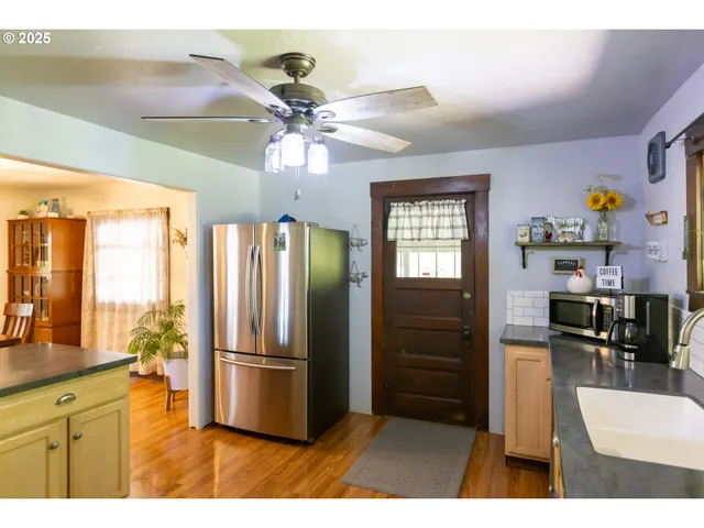 a kitchen with stainless steel appliances granite countertop a refrigerator a sink dishwasher a stove and a dining table with wooden floor