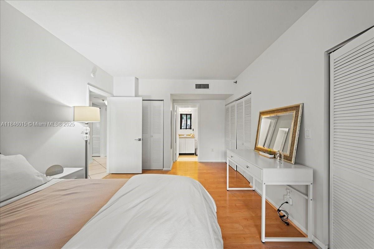 540 Brickell Key Drive, Unit 412 Miami, FL 33131 - Photo 21 of 33 a bedroom with a bed and a dresser with mirror