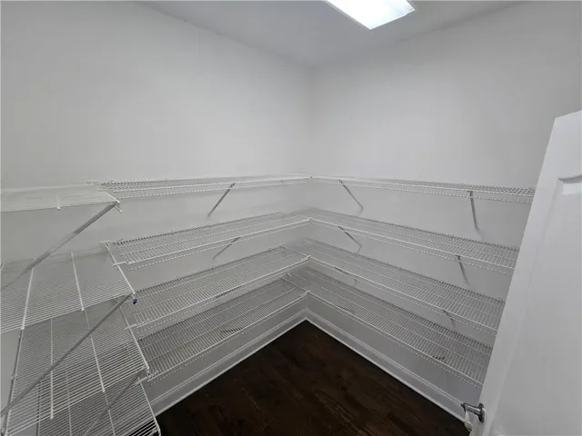 a view of an empty room with wooden floor fireplace and a window