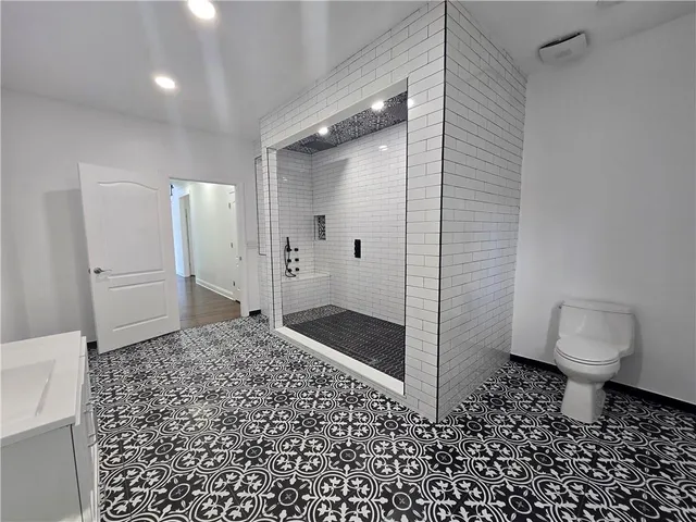 a view of a hallway with wooden floor and a bathroom