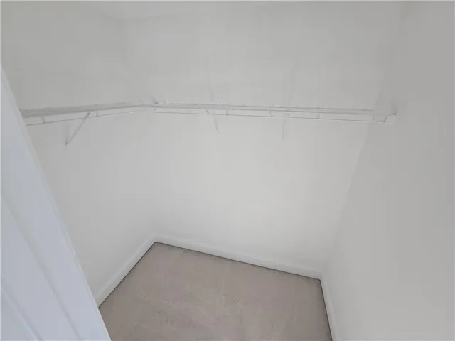 a view of an empty room with wooden floor and cabinets