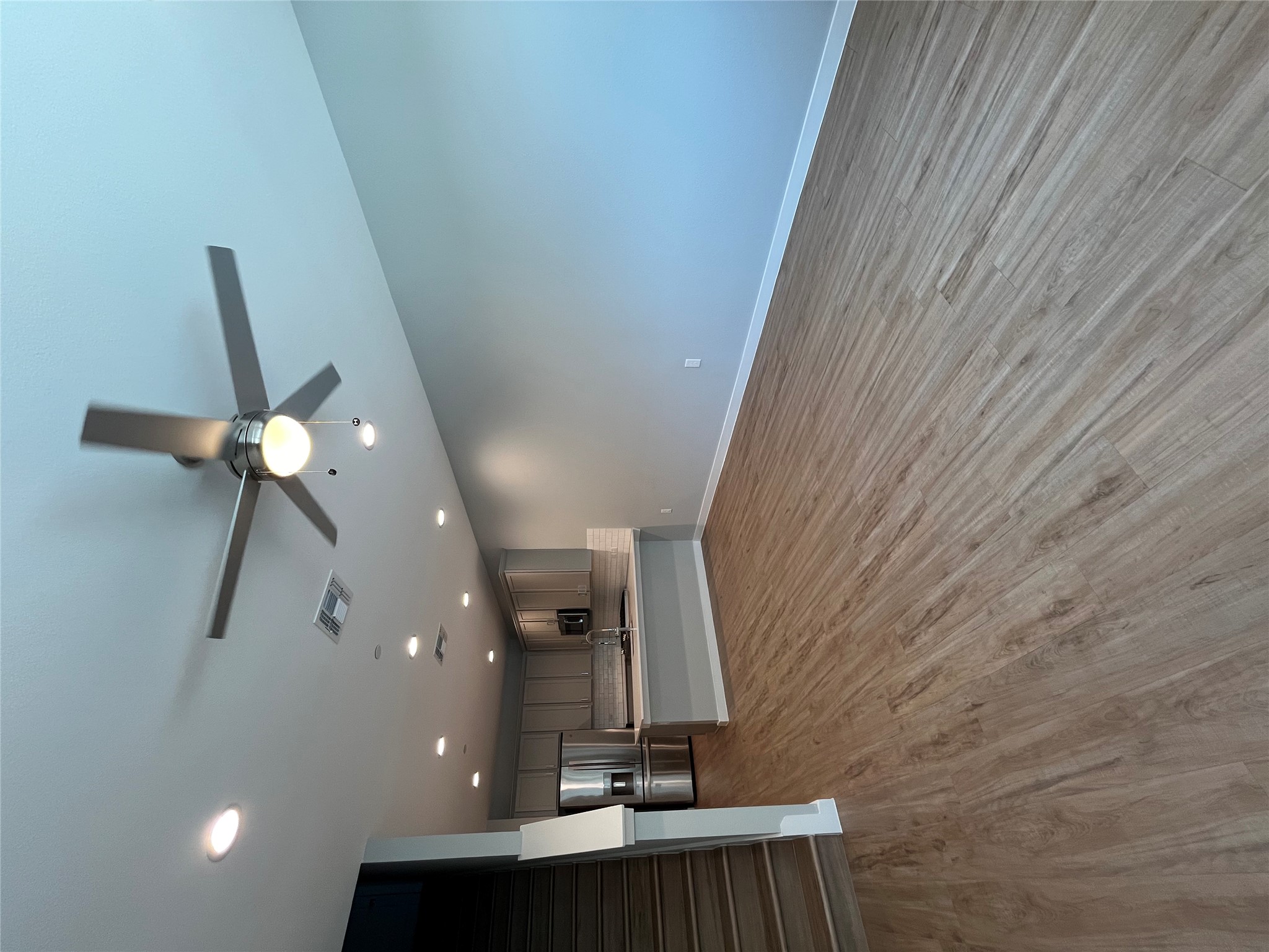 11409 Pastini Circle Manchaca, TX 78652 - Photo 7 of 18 an empty room with wooden floor a ceiling fan and kitchen view