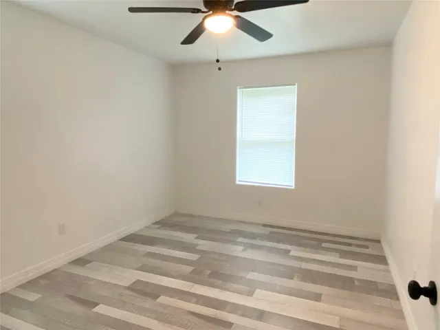 an empty room with a window and a ceiling fan