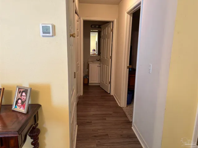 a view of a hallway with wooden floor and a bathroom