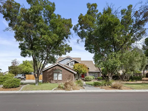 front view of house with a yard and trees all around