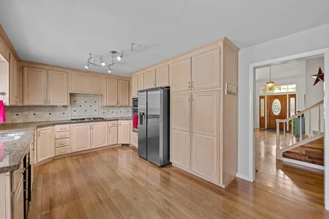 a kitchen with granite countertop a refrigerator sink and cabinets